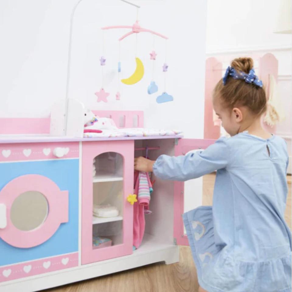 Little girl in blue putting doll clothing away in her play nursery station within their baby doll changing station by Sophia's. OLIVIA'S LITTLE WORLD WOODEN 6-IN-1 BABY DOLL CHANGING STATION, PINK/PURPLE