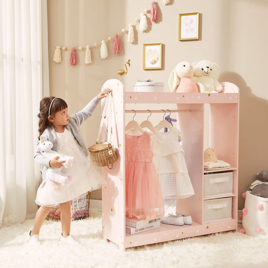 A young girl hangs her purse on the child sized clothing rack