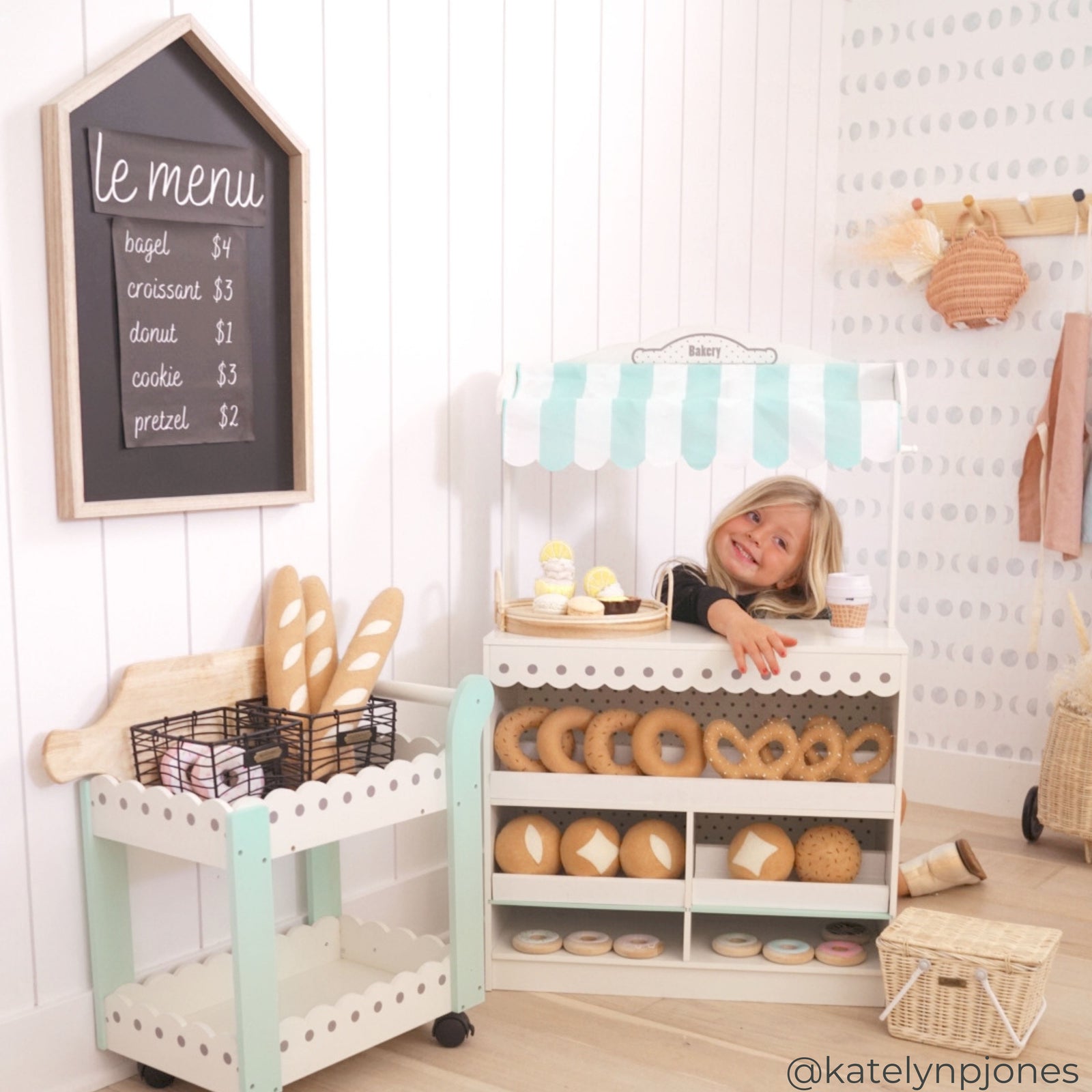 A girl smiling playing with Teamson Kids - My Dream Bakery shop Dessert Stand in a sunny room