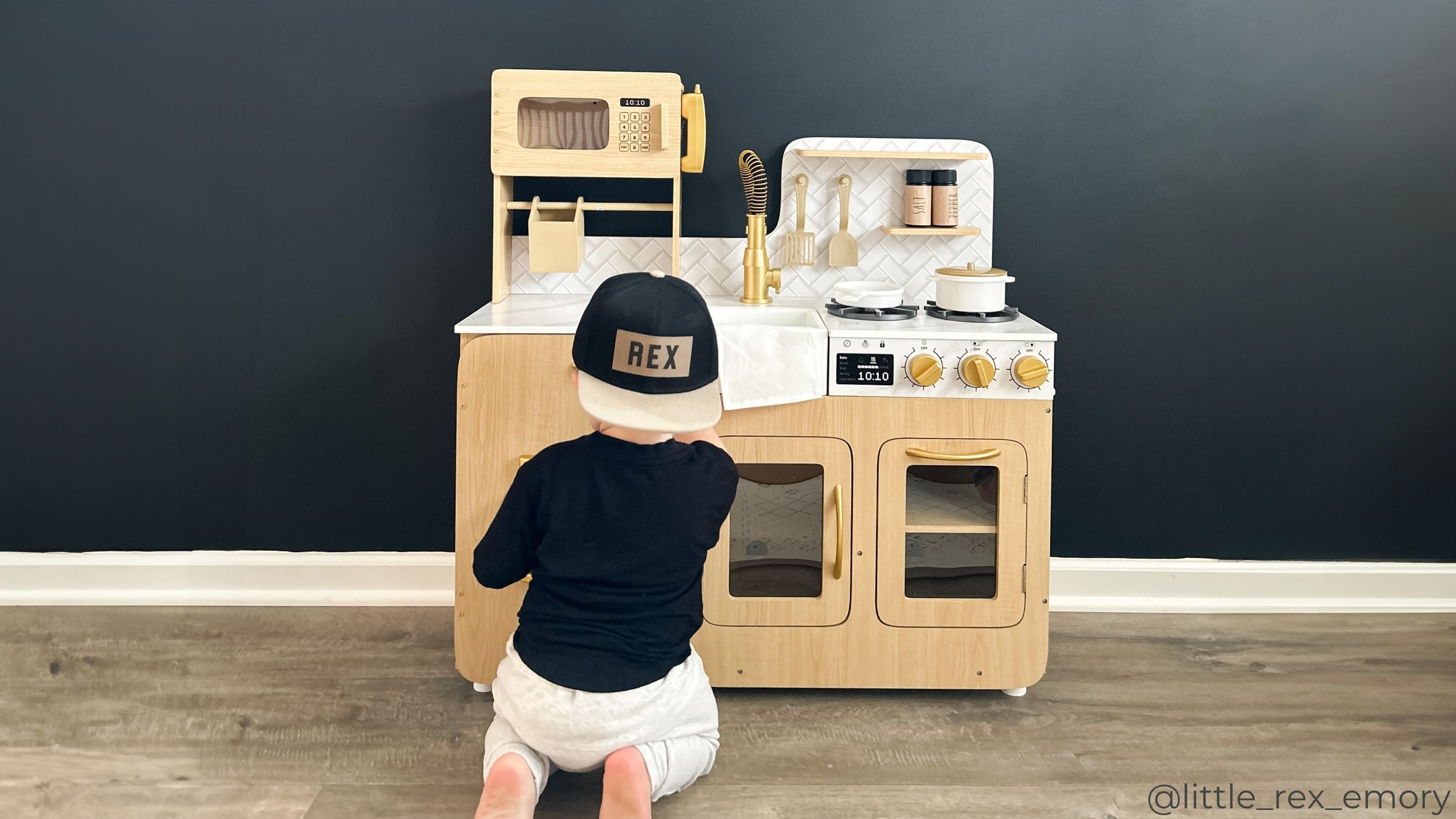 A boy playing with a light oak play kitchen