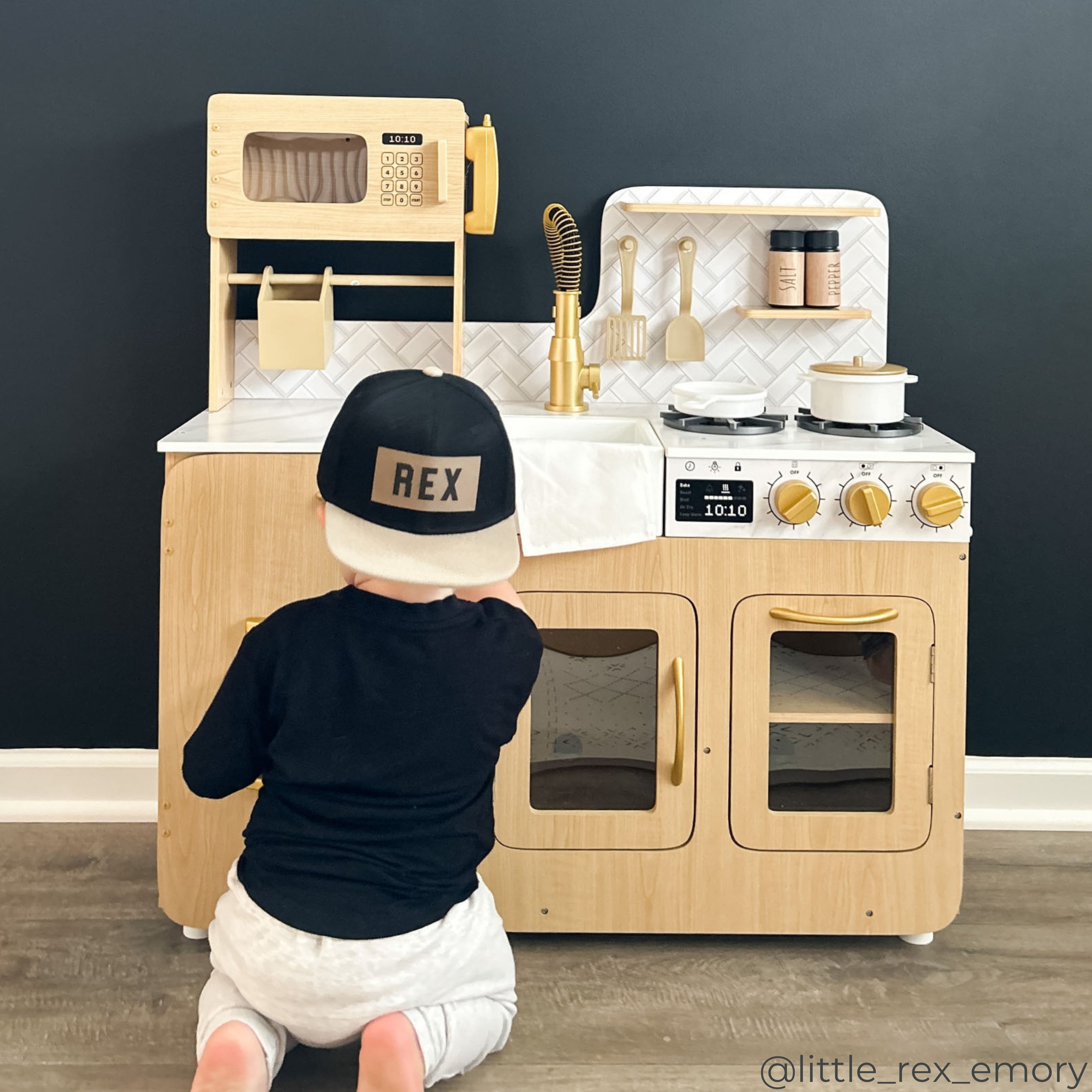 A boy playing with a light oak play kitchen