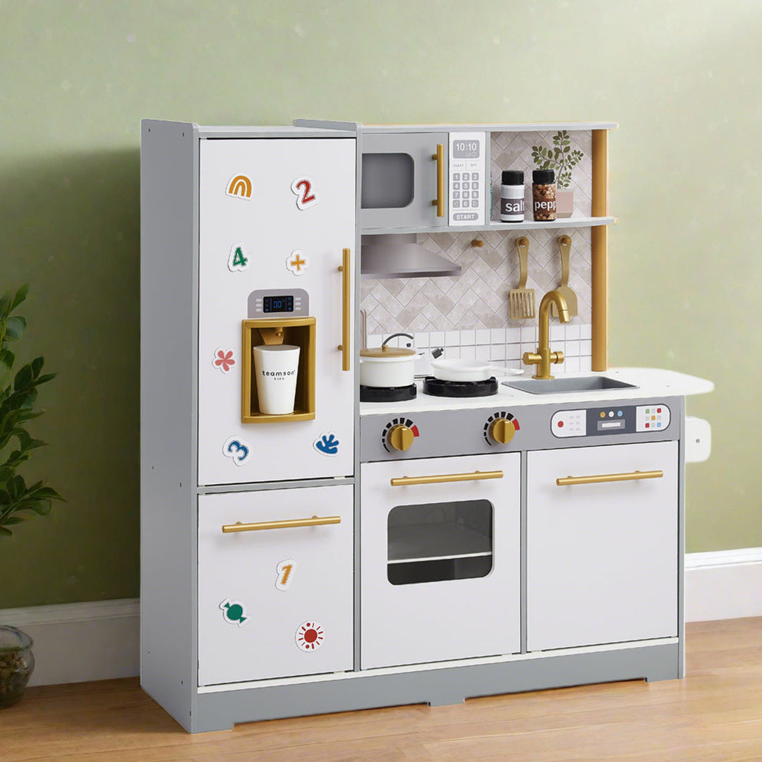 gray and white kitchen stands in a living room, has magnets on the fridge doors and cookware on the stove