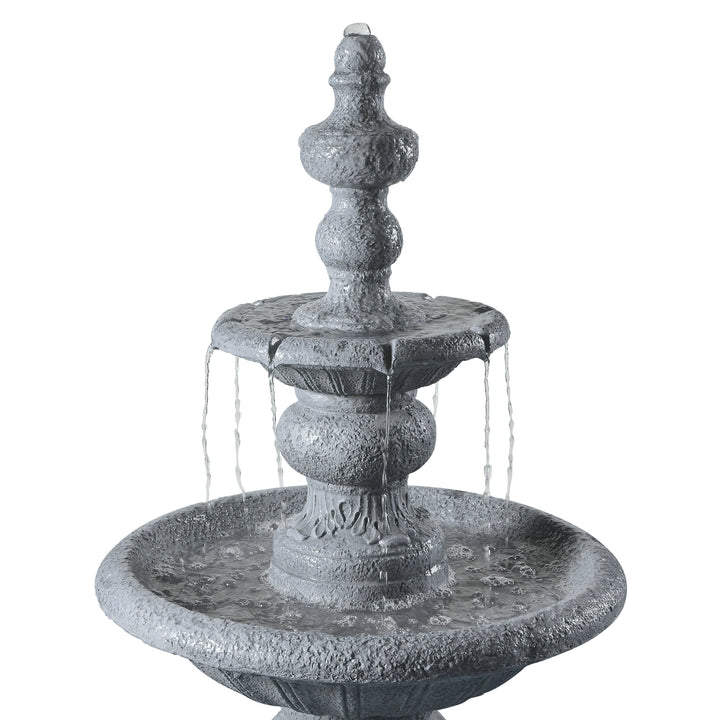 Closeup of water falling down a two-tier faux gray stone birdbath water fountain