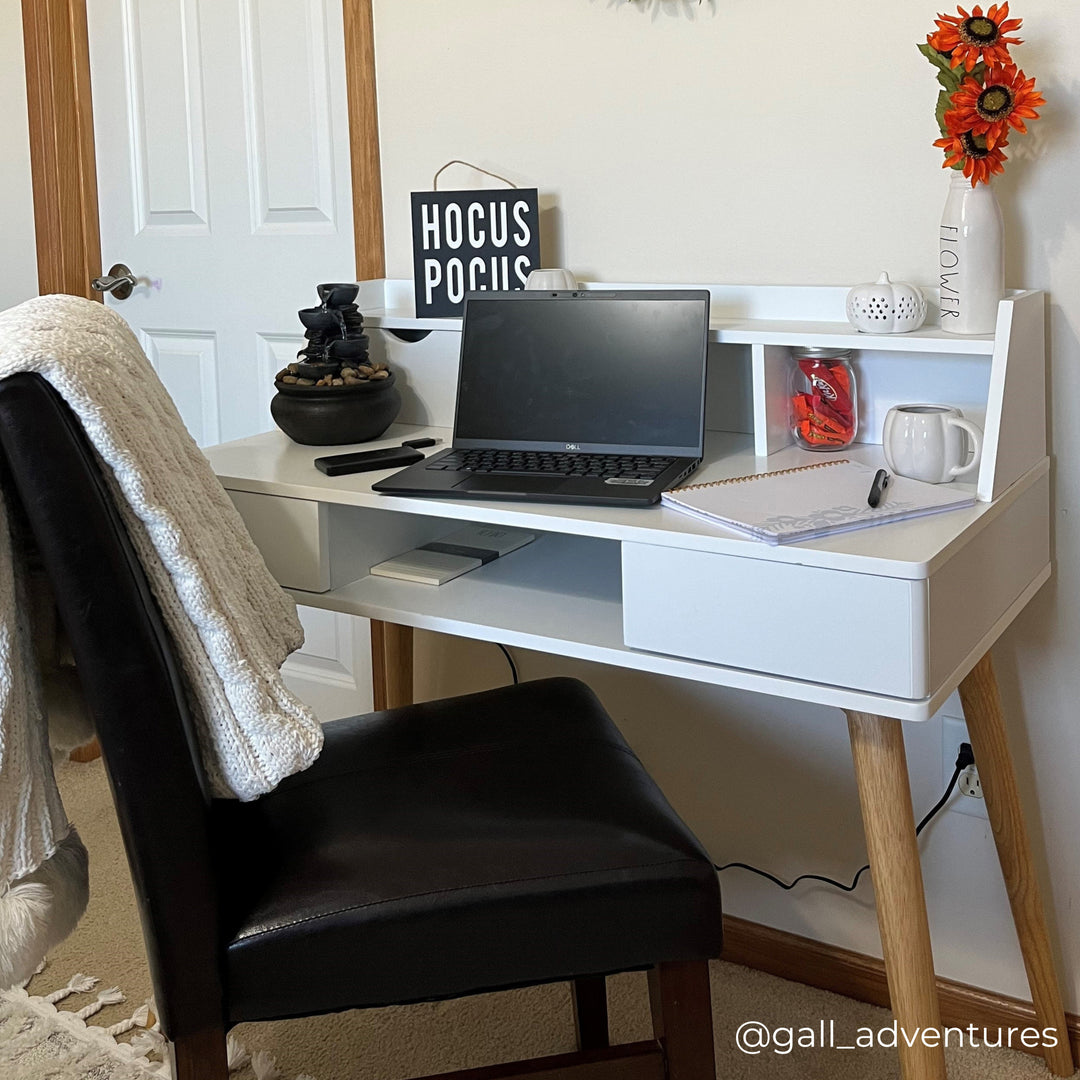 A home office with a white writing desk and black leather chair