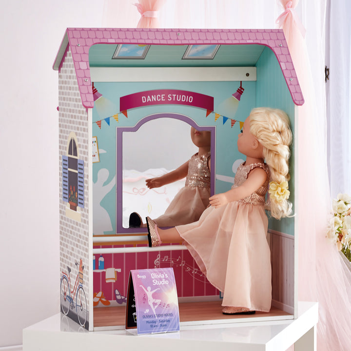 A 4-in-1 18" doll playset with the dance studio facade with a blonde doll dressed in a blush dress looking into the mirror.