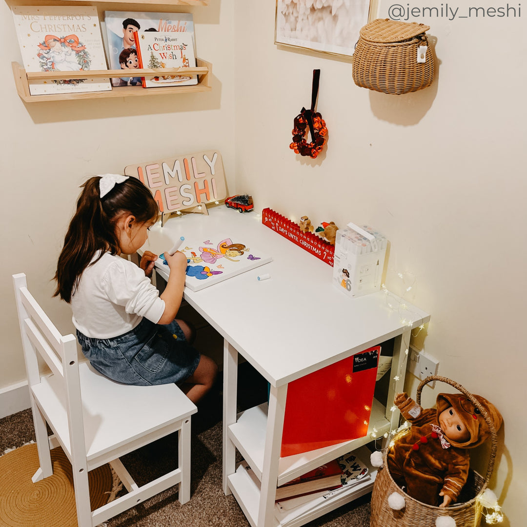 A girl sitting at a white desk coloring a picture