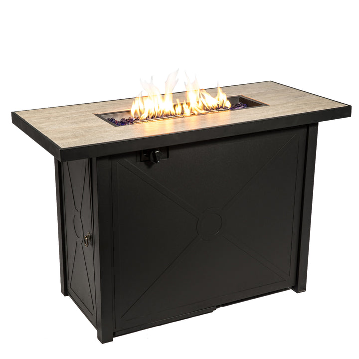 Elongated black propane gas fire pit table with a fire burning in the center on blue lava rocks