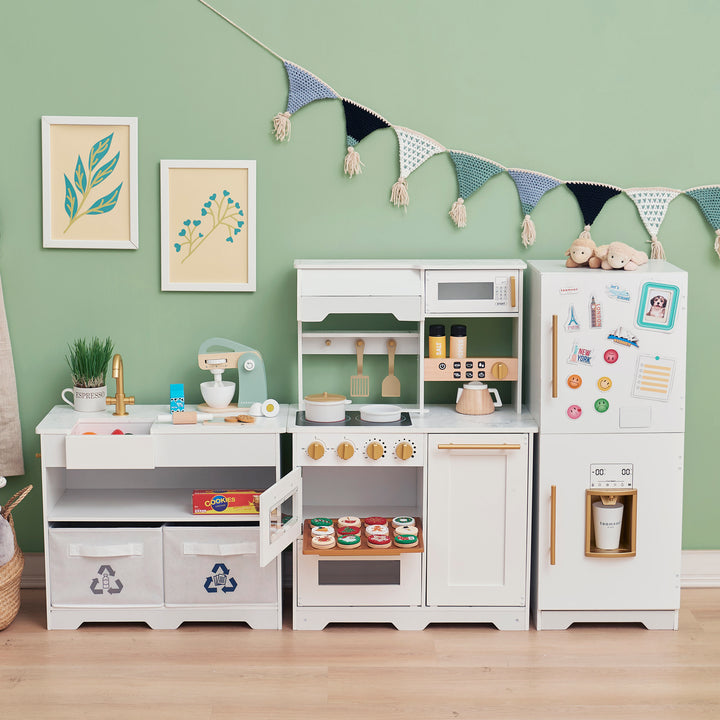 Little Chef Atlanta Large Modular Play Kitchen, white/gold arranged against a wall with accessories and decorations, creating a playful simulation of a kitchen environment for children.