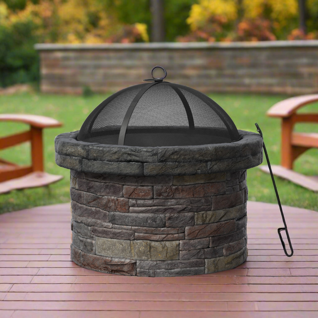 A round faux brick wood burning fire pit with a spark screen and poker on a redwood deck