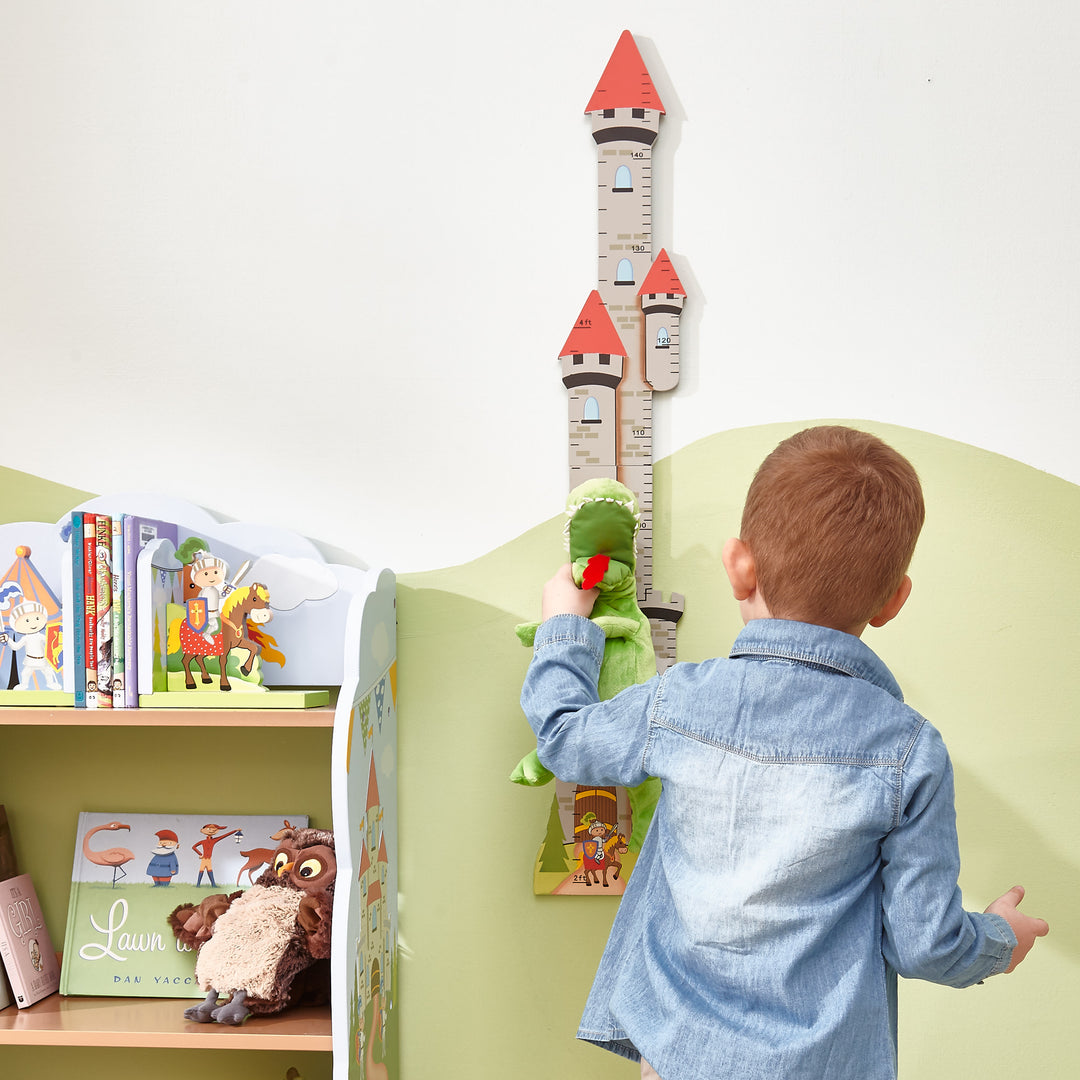 A boy is playing measuring his toy dinosaur against the growth chart in his room.