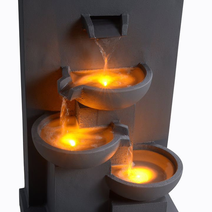 A view of the water flowing down each tier of this gray water fountain with the water illuminated from below