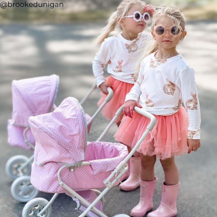 Two girls pushing classic-style pink play strollers