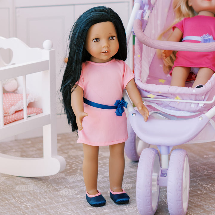 An 18" doll with black hair and pink dress and navy shoes