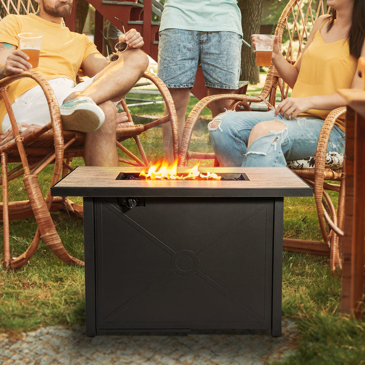 Three adults gathered around a black propane gas fire pit table