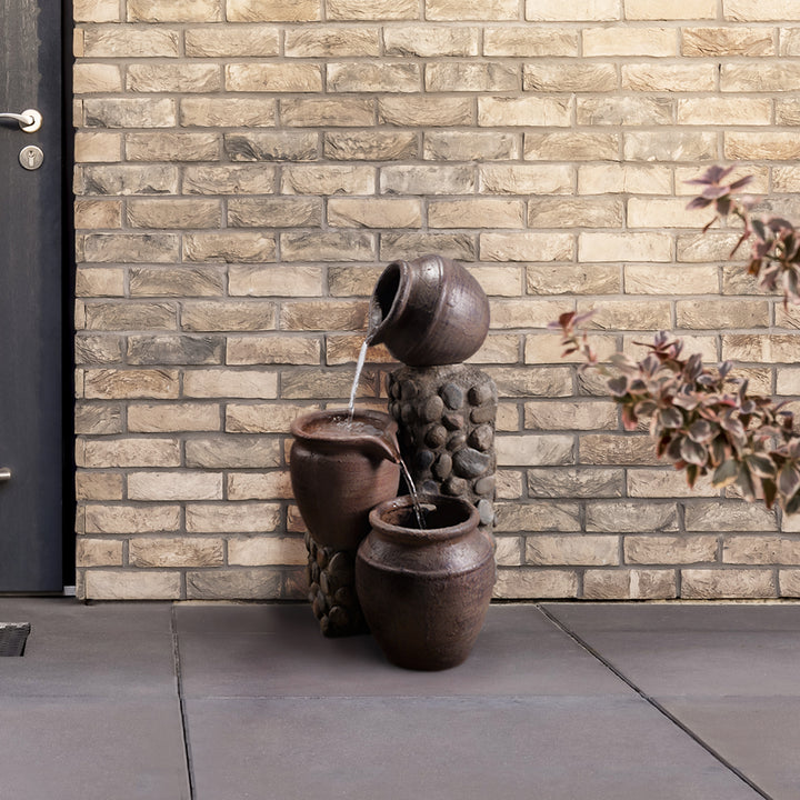 Fountain with "overflowing" pots in a backyard patio area.