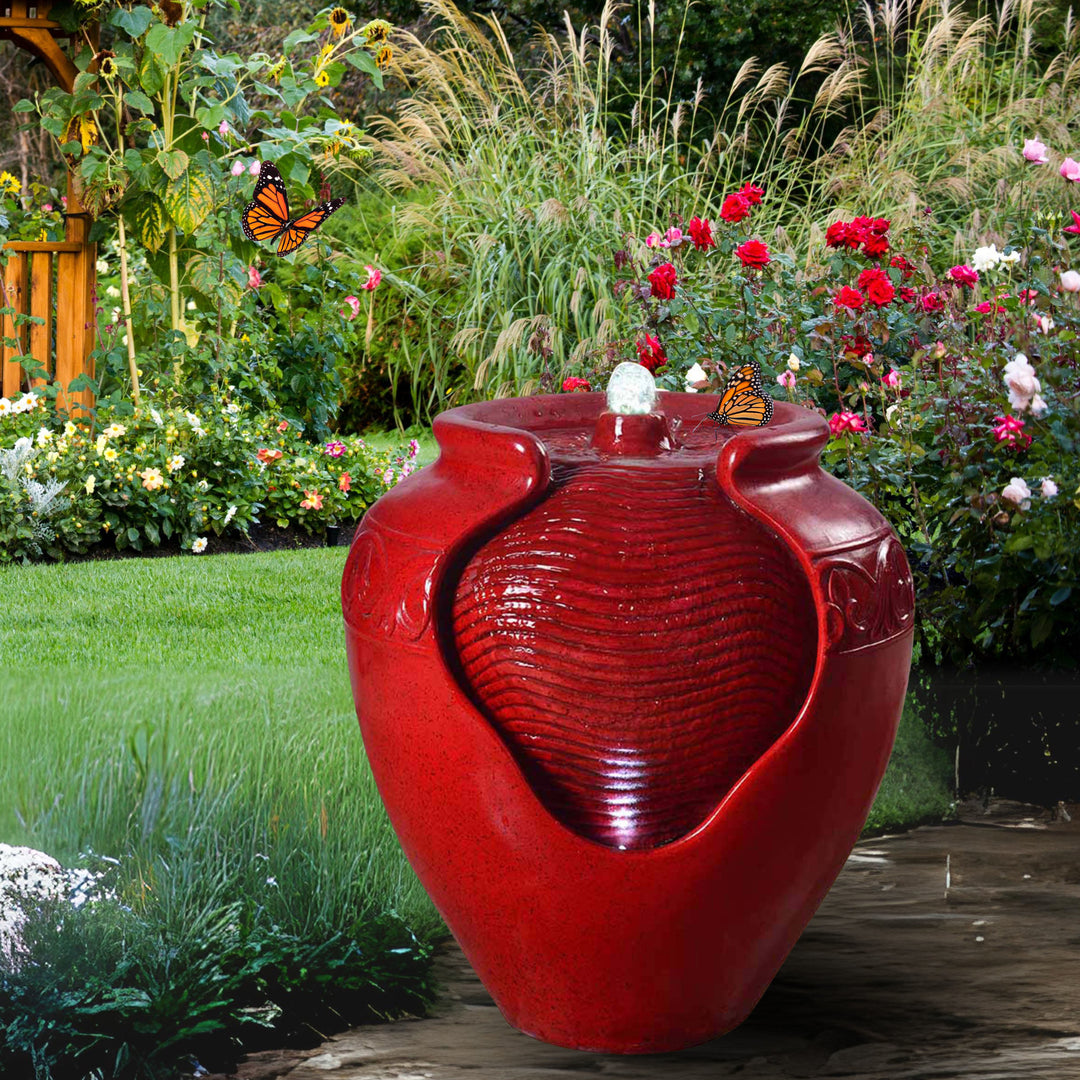 A red vase-style water fountain surrounded by butterflies and flowers