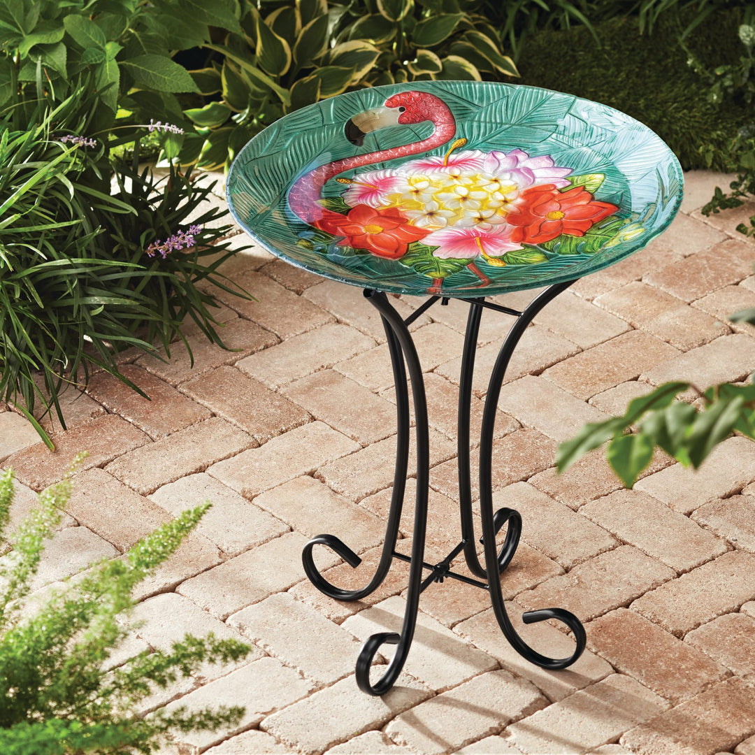 A 17.8" Fusion Glass Flamingo Design Birdbath with Metal Stand on a brick patio.