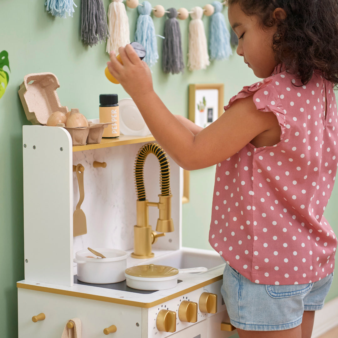 Young child playing with a Teamson Kids - Little Chef Memphis Small Play Kitchen, White/Gold.