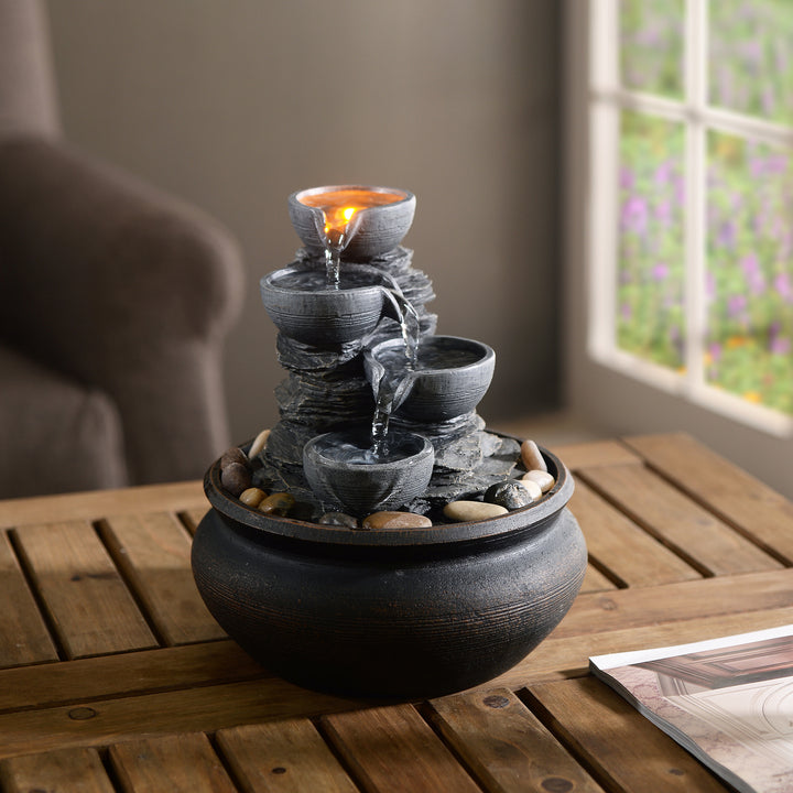 A tabletop cascading water fountain on a teak table