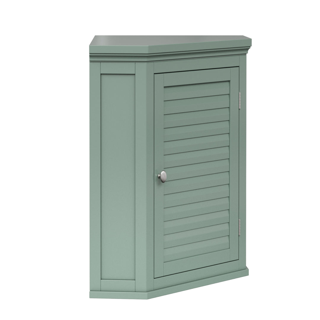 Side view of a sage green corner wall cabinet with faux louvered door and silver hardware.