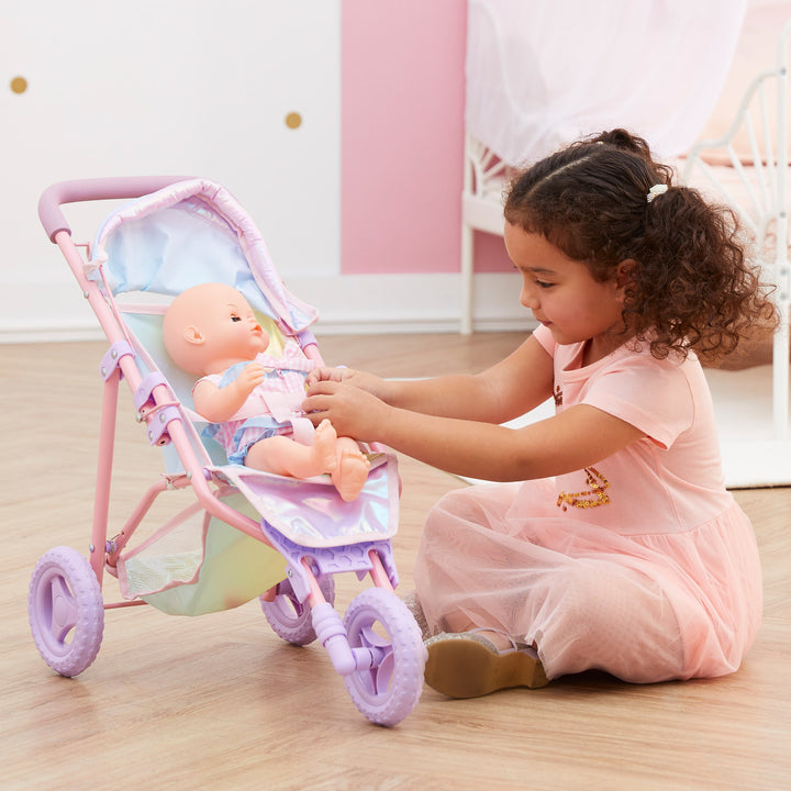 A little girl is playing with her baby doll in an iridescent baby doll jogging stroller.