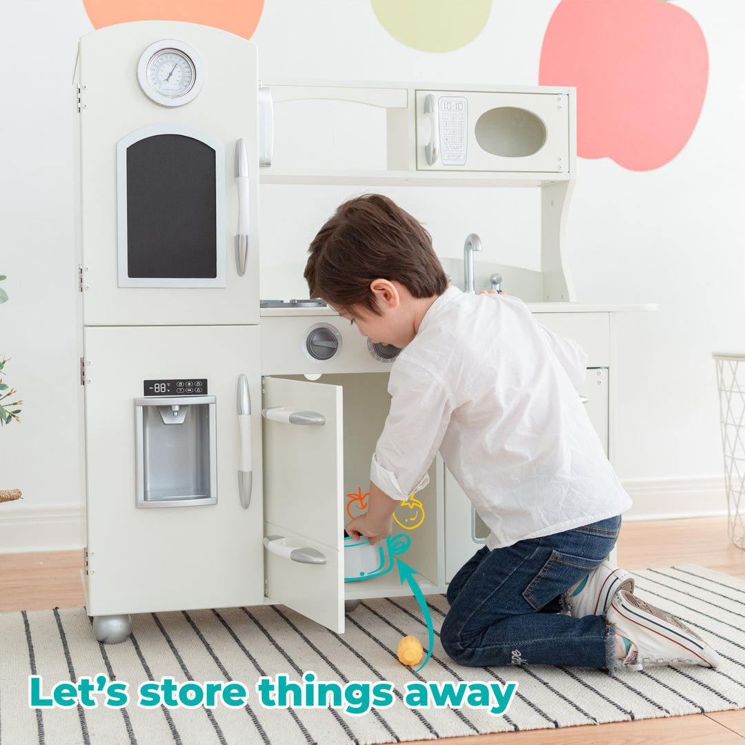 A child organizing toys in a Teamson Kids Little Chef Westchester Retro Kids Kitchen Playset, Ivory.