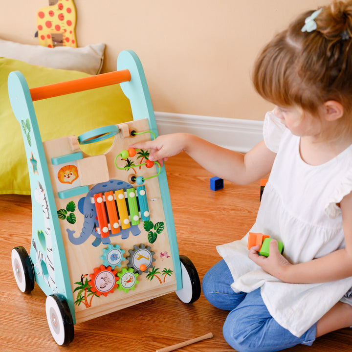 A little girl pushes beads down the wire path on the front of the baby walker and activity station.