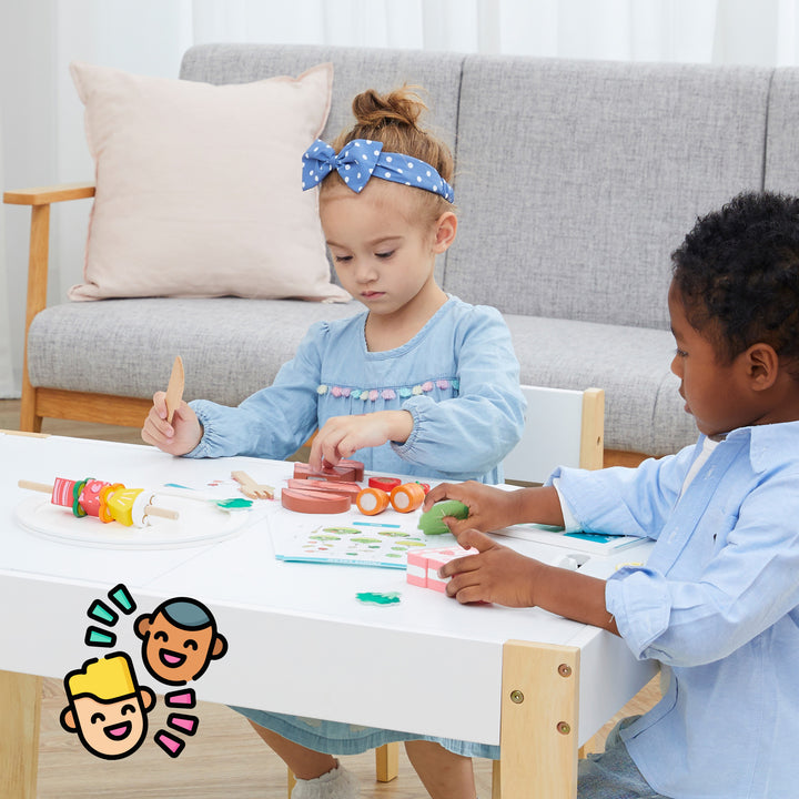 Two children engaged in playing with the Teamson Kids Little Chef Frankfurt 27 Piece Wooden Play Cooking Set at a table.