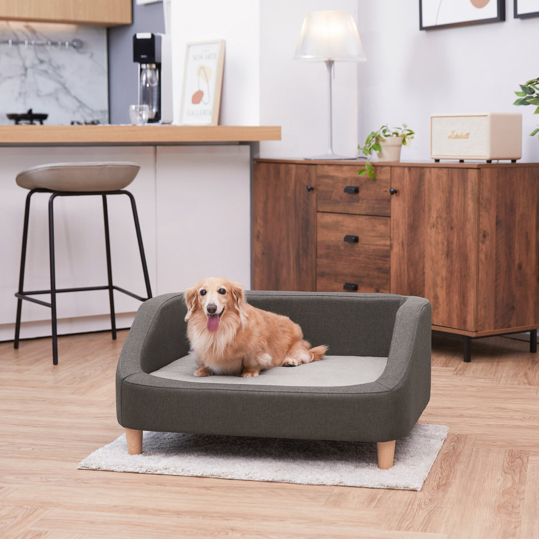 A two-tone gray Bennett Linen Sofa Pet Bed with a tan dog laying on it.