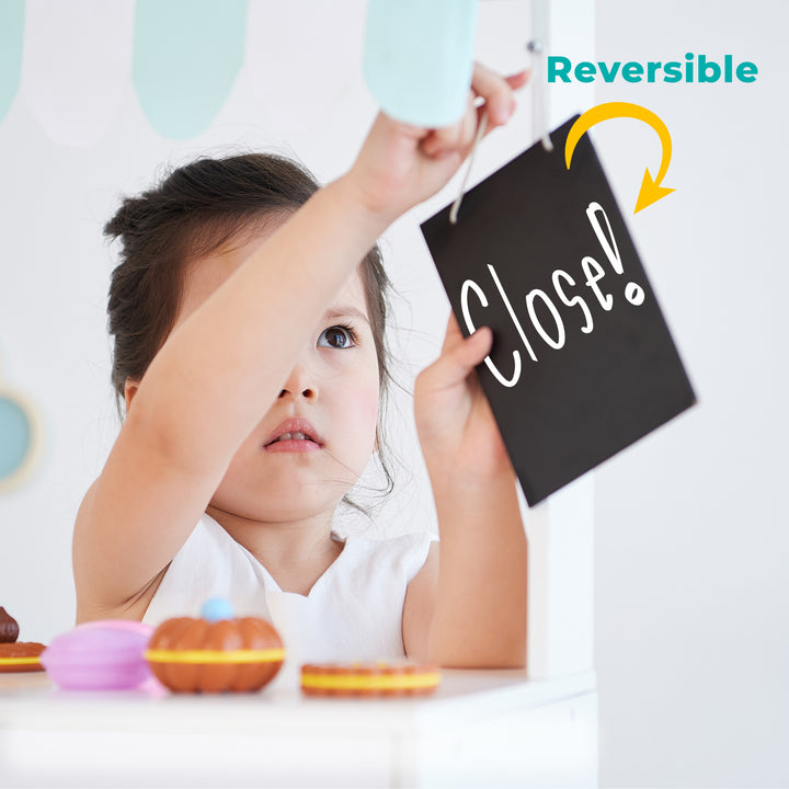 a young girl reverses the chalkboard sign from saying "Open!" to "Closed!"