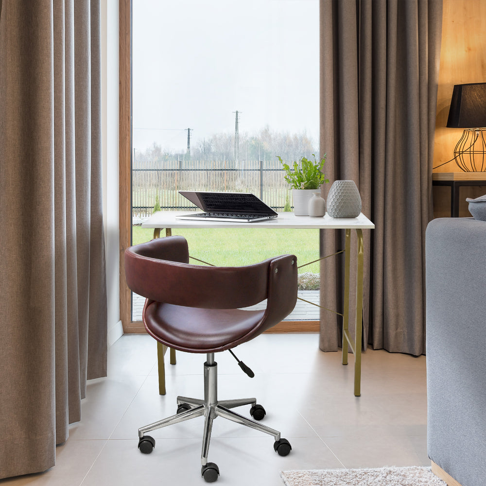 Teamson Home's Faux Brown Leather Mid-Century Modern Adjustable Office Chair sat at desk in front of a big window.