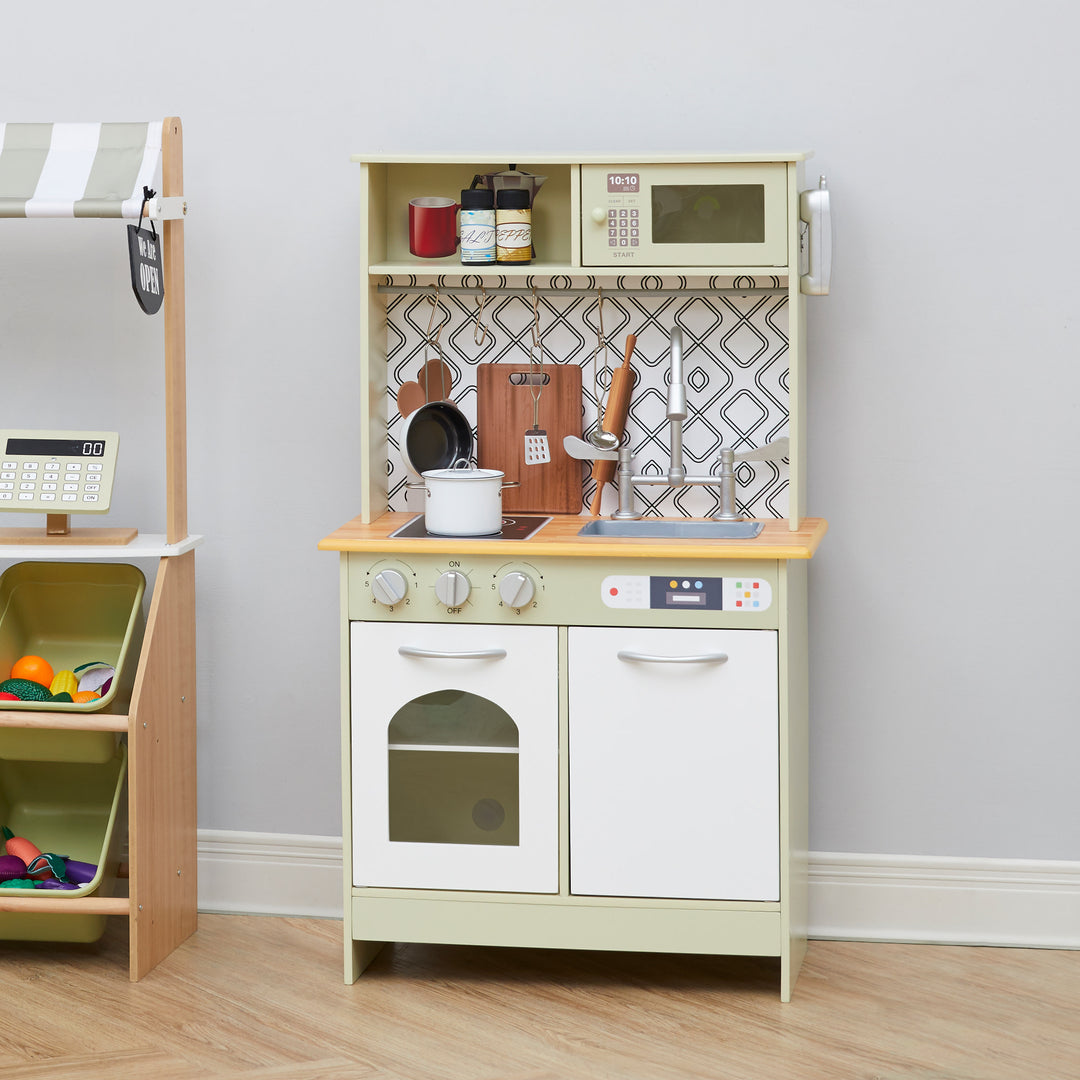 A play kitchen with a white pot on the stove, pretend seasonings on the top shelf, and a chrome farmhouse sink.