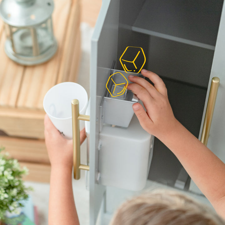 Child accessing a Teamson Kids Little Chef Charlotte Modern Play Kitchen, Silver Gray/Gold water dispenser with safety locks on the hot water taps in the kids' kitchen playset.