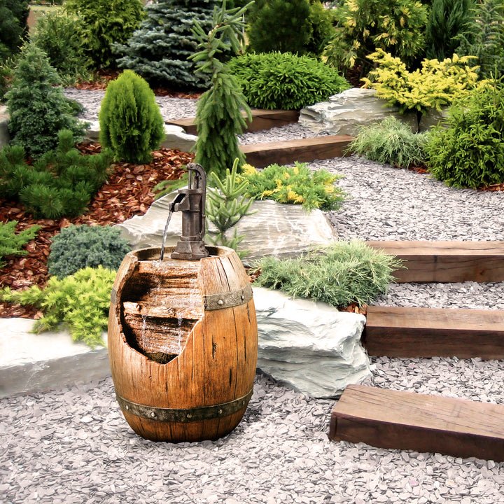 A Teamson Home Vintage Pump & Barrel water fountain in a landscaped setting