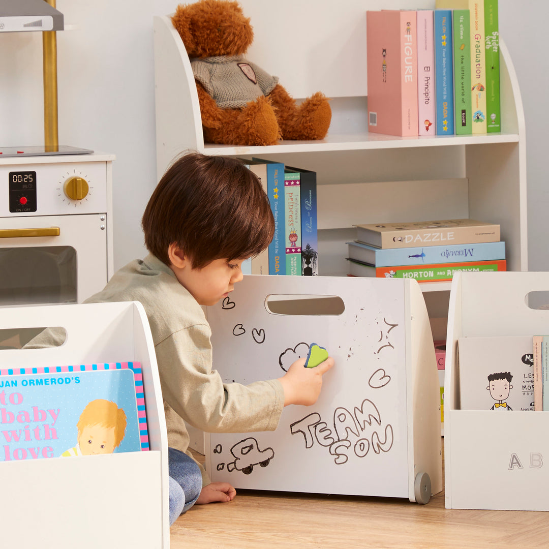 A little boy erasing his drawings from the dry erase surface of the portable bookcase.