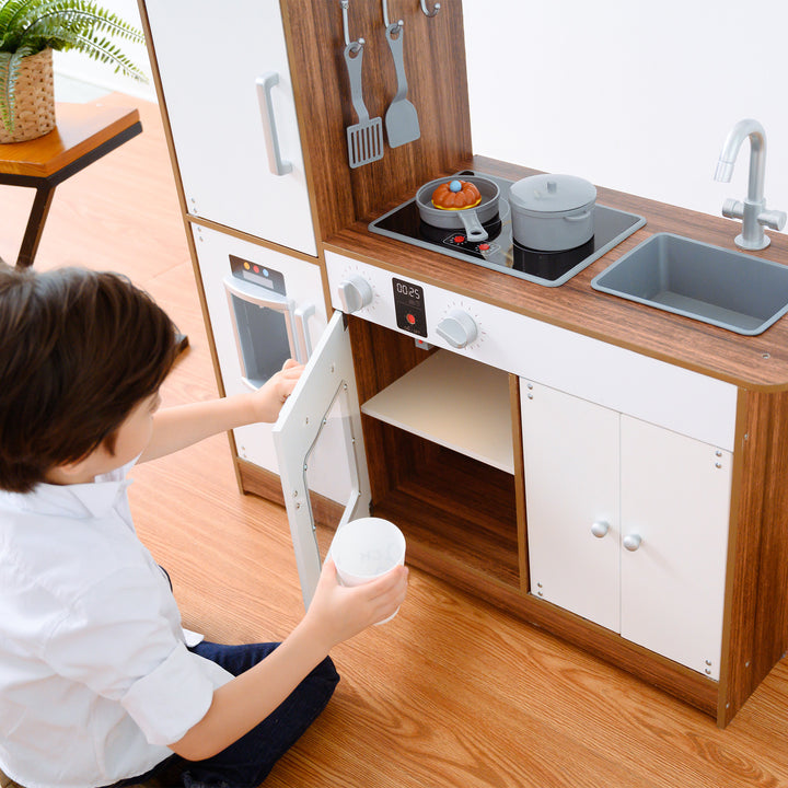 A child playing with a Teamson Kids Little Chef Palm Springs Classic Kids Play Kitchen with Accessories, Natural/White.