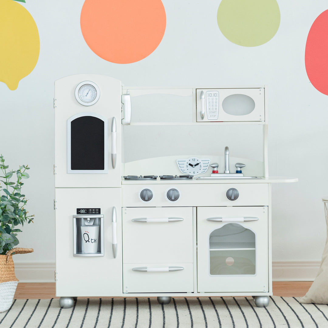 A retro style kids play kitchen with a chalkboard panel and ice dispenser on the refrigerator with a stove, sink and microwave