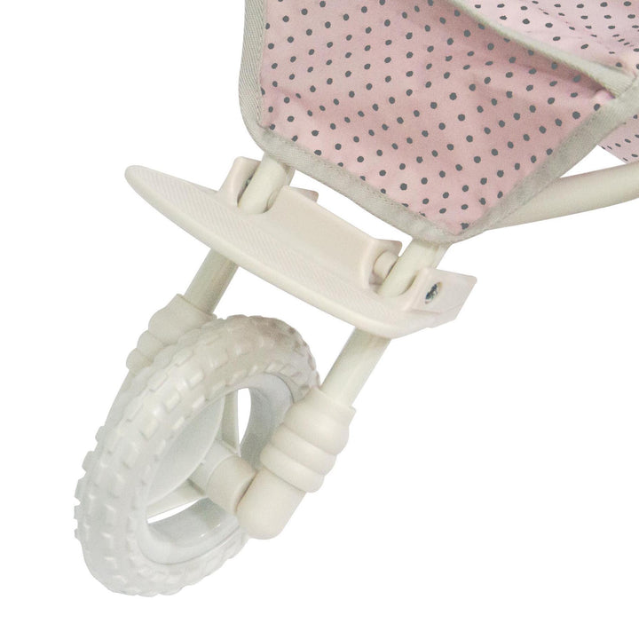 A close-up of the all-terrain white rubber wheel in the front of the baby doll stroller.