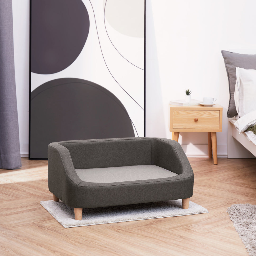 A two-tone gray Bennett Linen Sofa Pet Bed on a small rug in a bedroom.