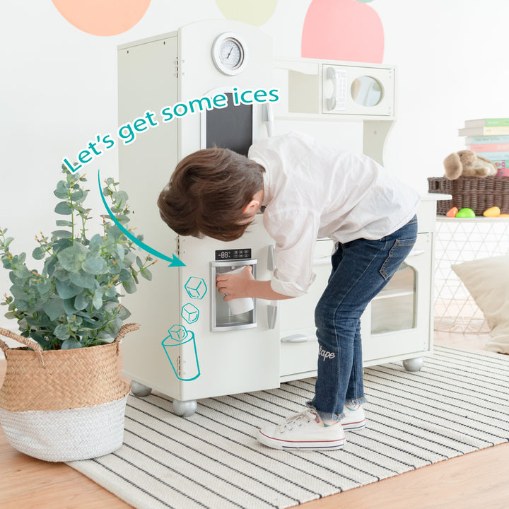 A child pretends to use a Teamson Kids Little Chef Westchester Retro Kids Kitchen Playset, Ivory with interactive features on a play kitchen set.