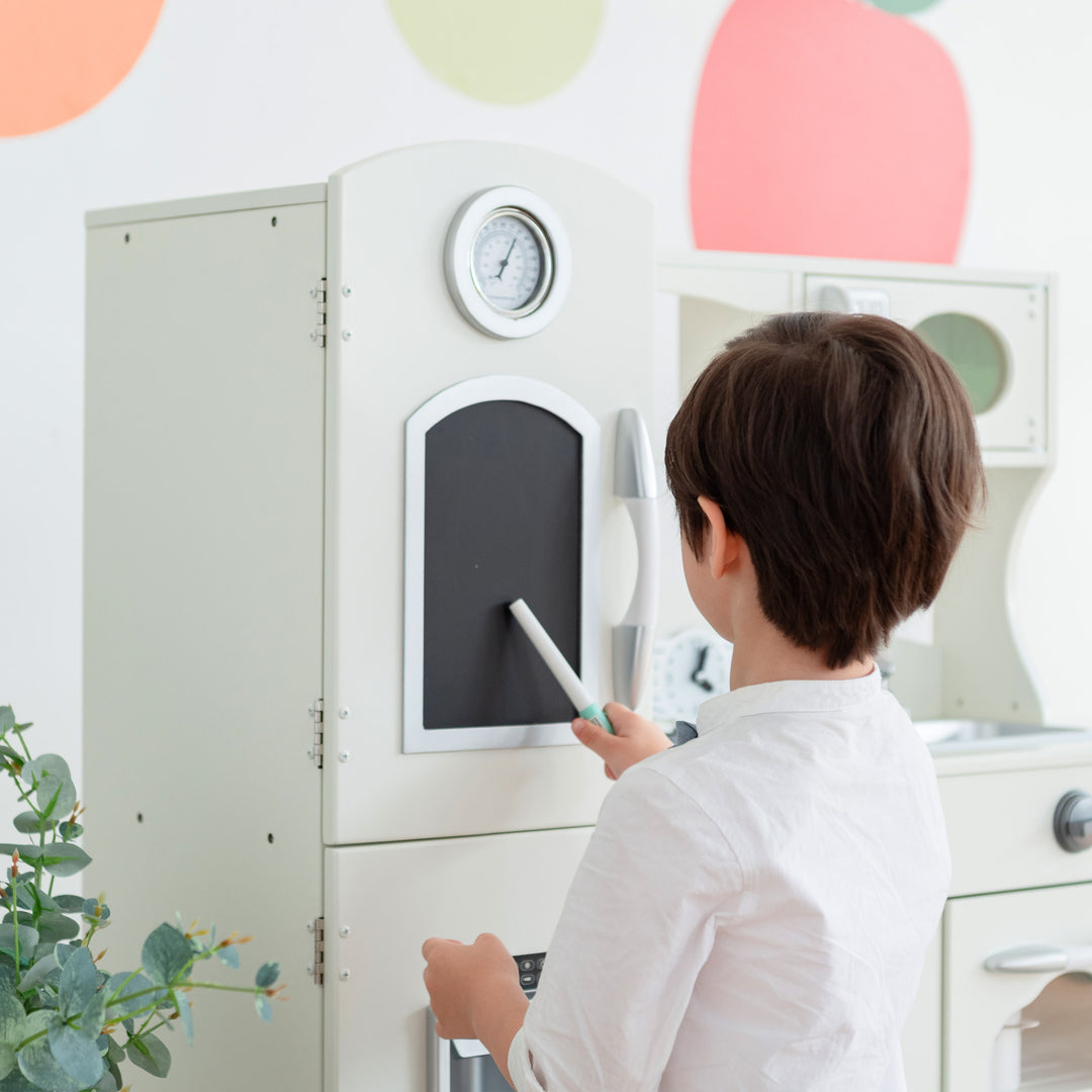 A child operating a Teamson Kids Little Chef Westchester Retro Kids Kitchen Playset, Ivory, complete with interactive features, like a toy telephone.